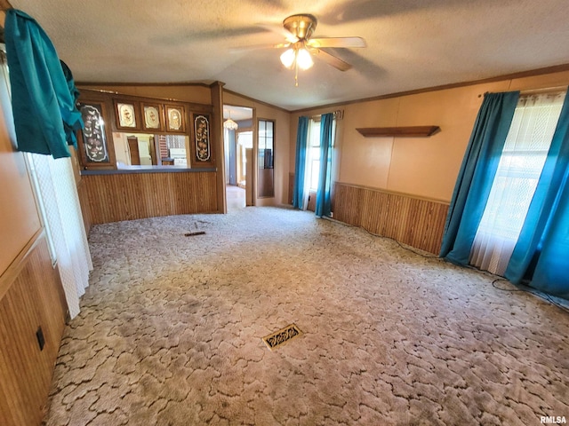 235 W 8th St, Flora, IL 62839 - empty room featuring carpet, lofted ceiling, a ceiling fan, wainscoting, and wood walls