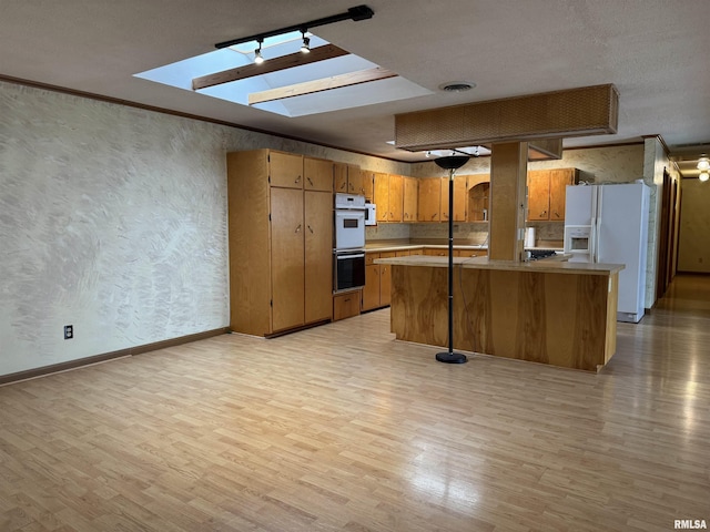 3100 Ava Rd, Murphysboro, IL 62994 - kitchen featuring white appliances, light wood finished floors, brown cabinets, a skylight, and light countertops