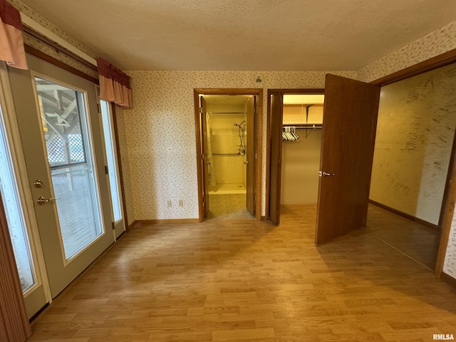 3100 Ava Rd, Murphysboro, IL 62994 - unfurnished bedroom featuring light wood finished floors, wallpapered walls, ensuite bathroom, a textured ceiling, and a closet