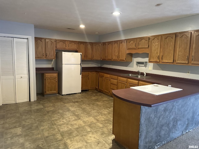 104 Mcneil St, Energy, IL 62933 - kitchen featuring freestanding refrigerator, dark countertops, brown cabinets, and a peninsula