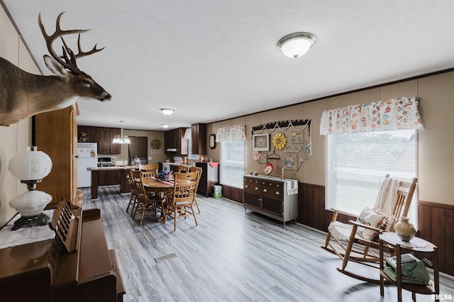 11149 Crenshaw Rd, Marion, IL 62922 - dining room with light wood-style floors, wainscoting, a chandelier, a textured ceiling, and wooden walls
