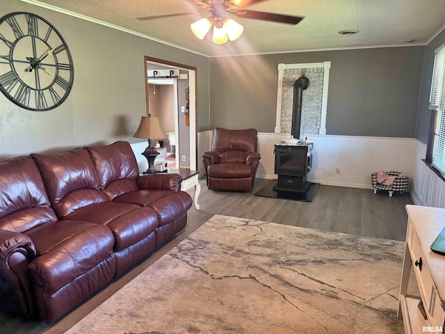 4139 Altenberger Rd, Metropolis, IL 62960 - living area with a wood stove, wood finished floors, ornamental molding, ceiling fan, and wainscoting
