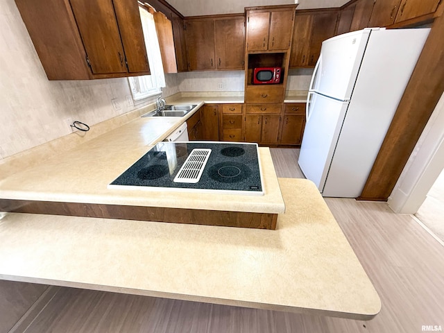 202 Flora Ave, Flora, IL 62839 - kitchen with freestanding refrigerator, stovetop with downdraft, light countertops, light wood-type flooring, and a peninsula
