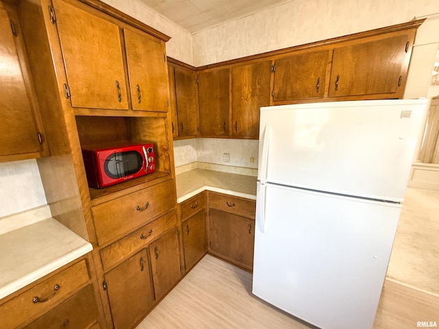 202 Flora Ave, Flora, IL 62839 - kitchen with freestanding refrigerator, brown cabinetry, and light countertops