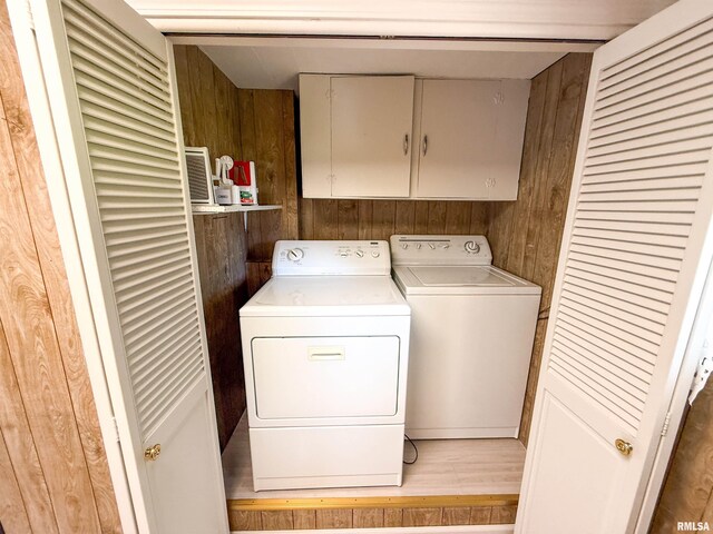202 Flora Ave, Flora, IL 62839 - laundry room featuring cabinet space, wooden walls, washing machine and clothes dryer, and light wood-style flooring