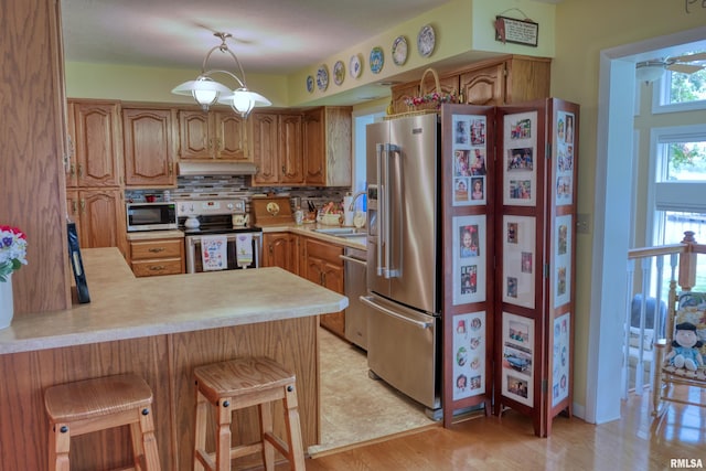 1382 Nicklaus Ln, Marion, IL 62959 - kitchen with appliances with stainless steel finishes, under cabinet range hood, light countertops, a peninsula, and backsplash