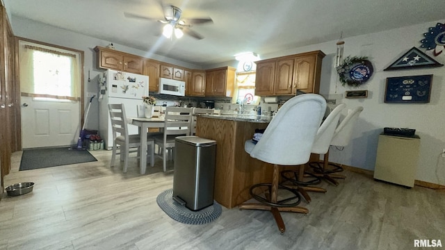 902 N Buchanan St, Benton, IL 62812 - kitchen featuring white appliances, a peninsula, ceiling fan, a breakfast bar, and healthy amount of natural light