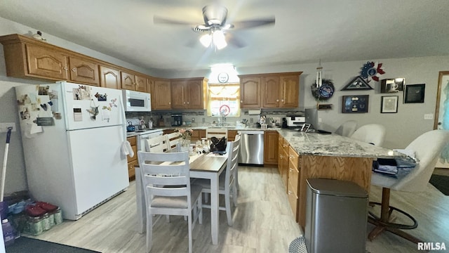 902 N Buchanan St, Benton, IL 62812 - kitchen featuring white appliances, a peninsula, a breakfast bar area, ceiling fan, and light wood-style flooring