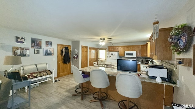 902 N Buchanan St, Benton, IL 62812 - kitchen with white appliances, a peninsula, light stone counters, brown cabinets, and ceiling fan