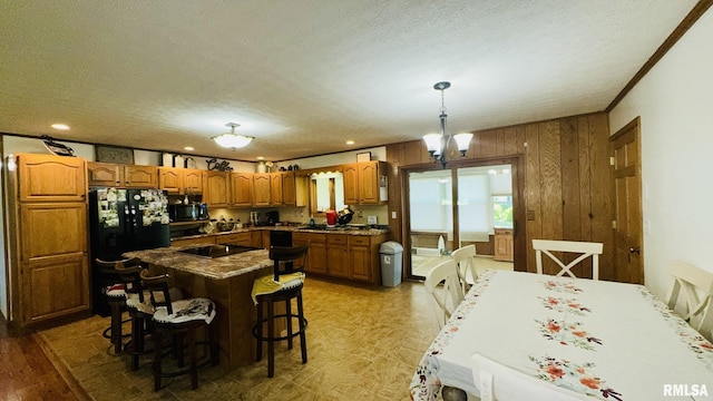 13919 Hamilton Pike Rd, Whittington, IL 62897 - kitchen featuring brown cabinets, black appliances, a textured ceiling, a kitchen breakfast bar, and a center island