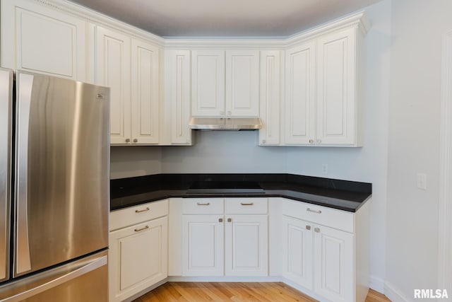 1506 Gleneagle Dr, Marion, IL 62959 - kitchen with freestanding refrigerator, black electric stovetop, under cabinet range hood, dark countertops, and light wood-type flooring