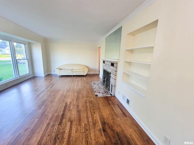 119 S 6th St SE, Clay City, IL 62824 - unfurnished living room with built in shelves, dark wood-style floors, ornamental molding, and a fireplace
