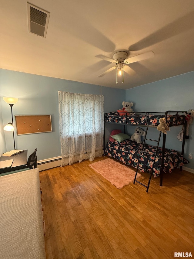 303 S College Blvd, Carmi, IL 62821 - bedroom with wood finished floors, baseboard heating, and a ceiling fan