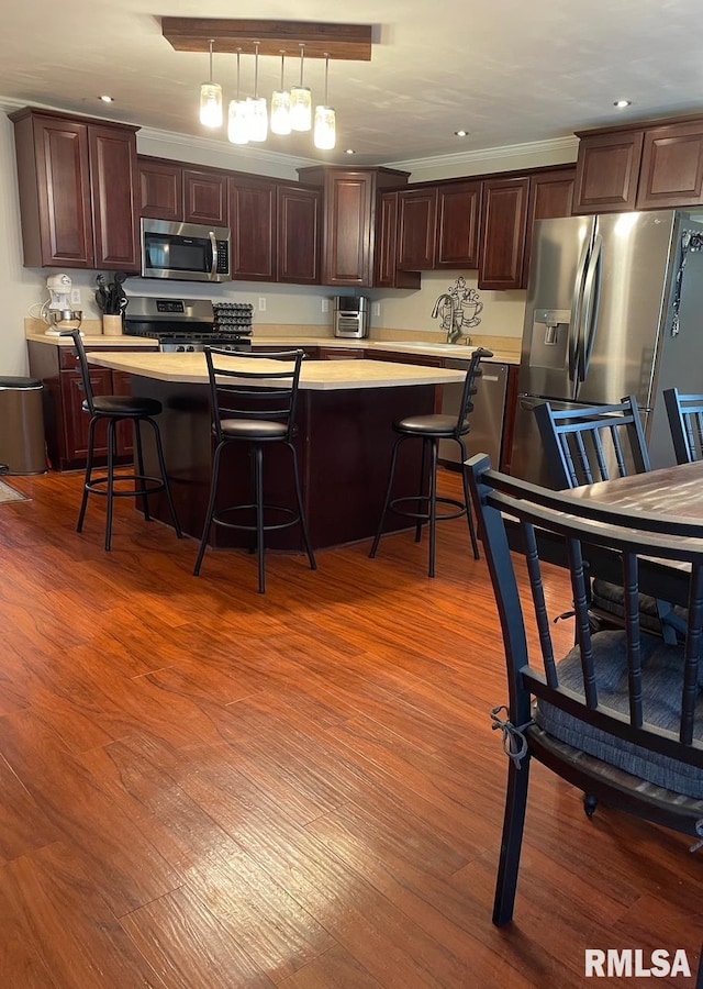 303 S College Blvd, Carmi, IL 62821 - kitchen with stainless steel appliances, light countertops, light wood-style floors, a breakfast bar, and a kitchen island
