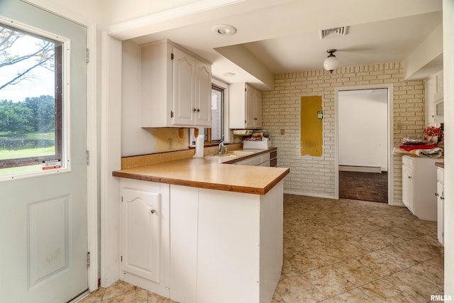 2723 Country Club Rd, Carbondale, IL 62901 - kitchen featuring brick wall, healthy amount of natural light, light countertops, white cabinetry, and a peninsula