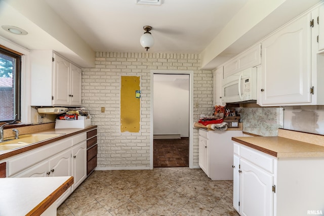 2723 Country Club Rd, Carbondale, IL 62901 - kitchen featuring white microwave, brick wall, white cabinetry, light countertops, and a baseboard heating unit