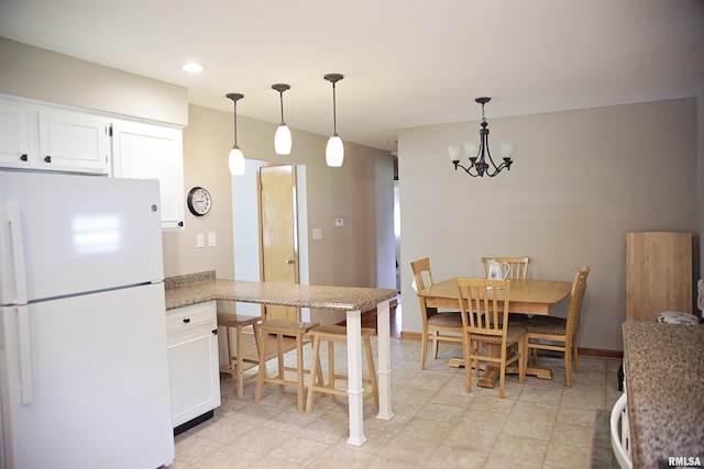 203 Skyline Dr, Marion, IL 62959 - kitchen with freestanding refrigerator, a chandelier, white cabinetry, hanging light fixtures, and a peninsula