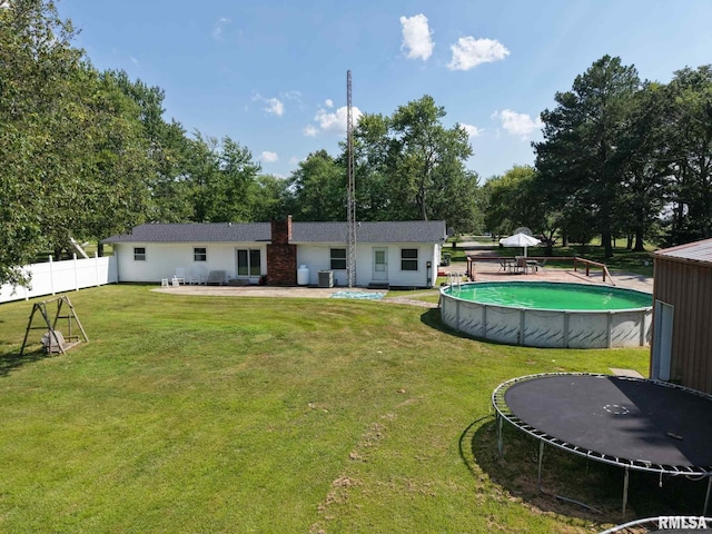 13607 Leisure Ln, Benton, IL 62812 - rear view of property featuring a trampoline, an outdoor pool, view of wooded area, and a chimney
