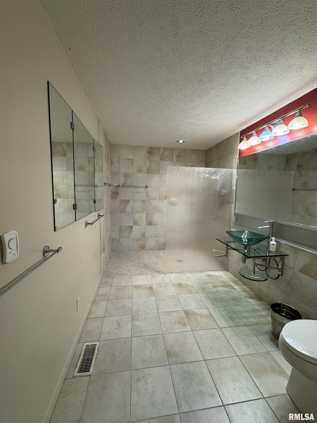 1308 Shawnee Trl, Carterville, IL 62918 - bathroom featuring a walk in shower, a textured ceiling, tile patterned flooring, and tile walls
