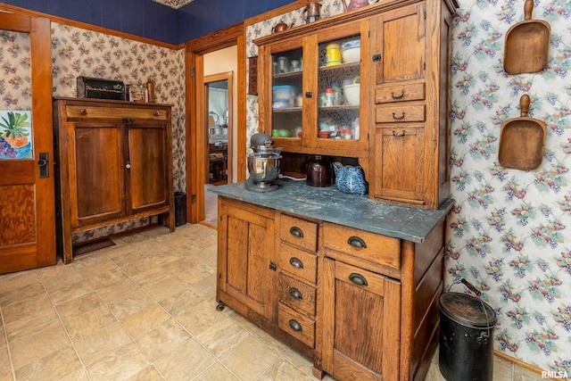 2011 Logan St, Murphysboro, IL 62966 - kitchen featuring wallpapered walls, glass insert cabinets, brown cabinetry, and dark countertops