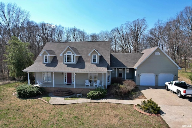 43 E Lakewood Dr, Metropolis, IL 62960 - cape cod house featuring concrete driveway, covered porch, an attached garage, and a front yard