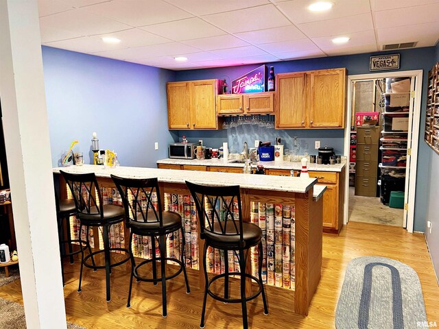 43 E Lakewood Dr, Metropolis, IL 62960 - kitchen with stainless steel microwave, a kitchen bar, a peninsula, light wood-type flooring, and a paneled ceiling