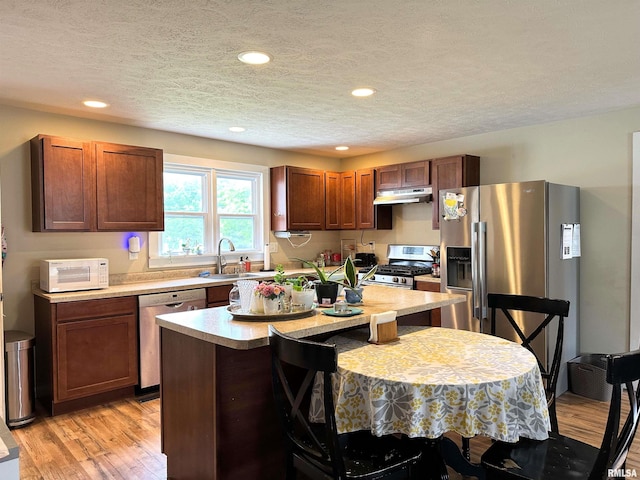 501 Cedar Creek Rd, Makanda, IL 62958 - kitchen featuring appliances with stainless steel finishes, under cabinet range hood, a textured ceiling, light countertops, and a center island