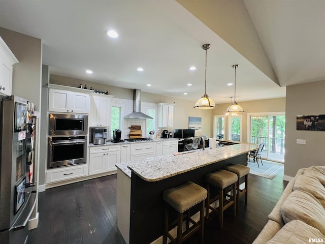 65 Stony Pt, Goreville, IL 62939 - kitchen with stainless steel appliances, wall chimney range hood, recessed lighting, a breakfast bar, and white cabinets