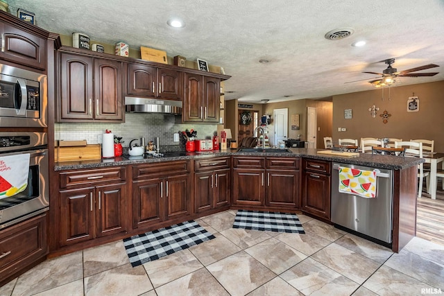13399 S County Line Rd, West Frankfort, IL 62896 - kitchen with appliances with stainless steel finishes, a peninsula, under cabinet range hood, a ceiling fan, and decorative backsplash