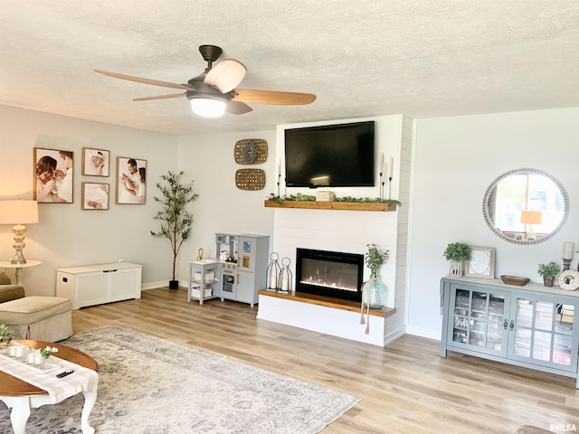 1203 W Goodall St, Marion, IL 62959 - living room featuring wood finished floors, a ceiling fan, a textured ceiling, and a glass covered fireplace