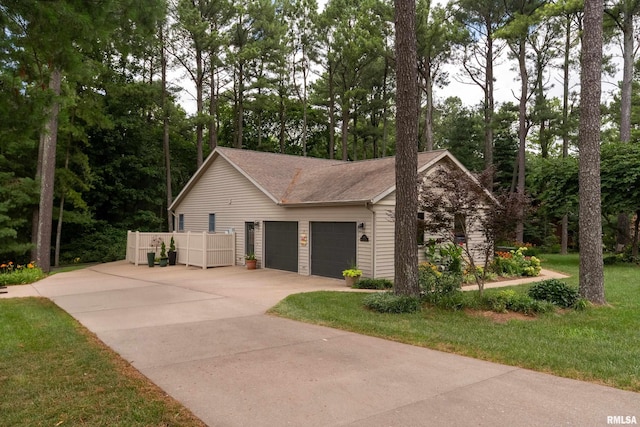 103 Woodland Trl, Anna, IL 62906 - view of property exterior featuring a garage, concrete driveway, a shingled roof, view of scattered trees, and a lawn