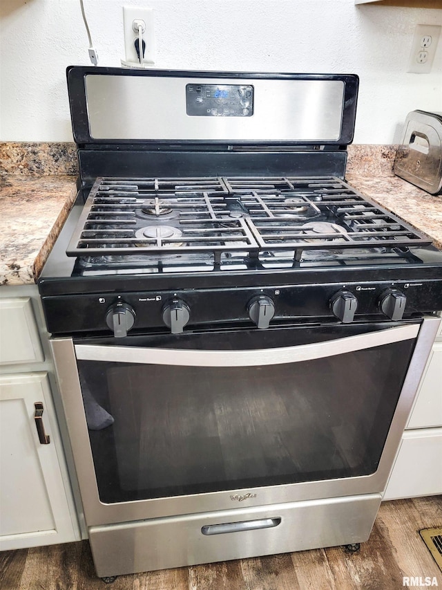 232 Palm Ln, Flora, IL 62839 - kitchen view of stainless steel gas range, wood finished floors, white cabinets, and light countertops