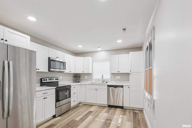 302 S Gray Dr, Carbondale, IL 62901 - kitchen with appliances with stainless steel finishes, white cabinets, light countertops, light wood-style floors, and recessed lighting
