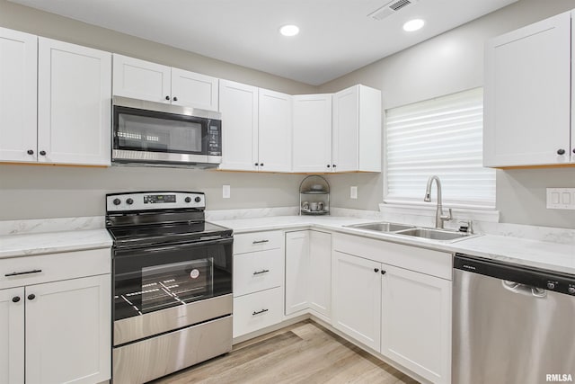 302 S Gray Dr, Carbondale, IL 62901 - kitchen with stainless steel appliances, white cabinetry, light wood-style floors, light stone countertops, and recessed lighting