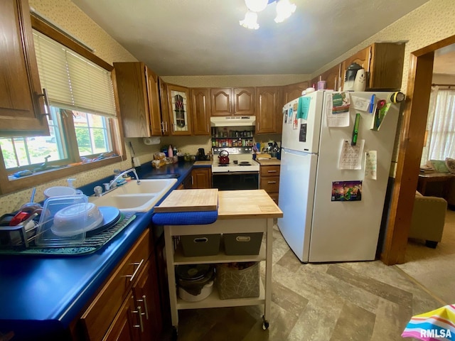 1915 E Oak St, West Frankfort, IL 62896 - kitchen with white appliances, under cabinet range hood, brown cabinets, and healthy amount of natural light