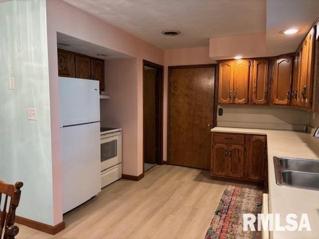 15944 Moellers Rd, Marion, IL 62959 - kitchen featuring white appliances, light wood-style floors, light countertops, recessed lighting, and brown cabinets