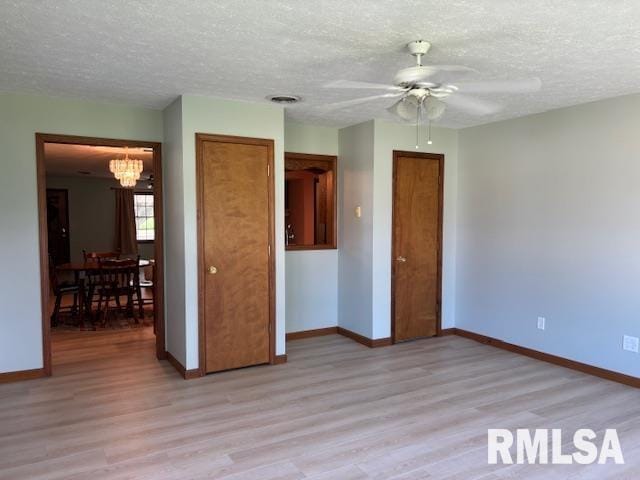 15944 Moellers Rd, Marion, IL 62959 - unfurnished bedroom featuring light wood finished floors, a chandelier, a textured ceiling, a ceiling fan, and a closet