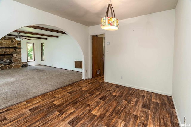 1811 W Freeman St, Carbondale, IL 62901 - empty room with arched walkways, a ceiling fan, wood finished floors, a stone fireplace, and beam ceiling
