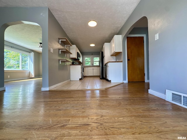 403 Freeman St, Anna, IL 62906 - kitchen featuring arched walkways, white cabinetry, stainless steel appliances, light wood-type flooring, and healthy amount of natural light