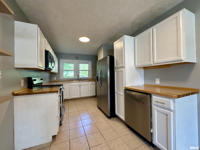 403 Freeman St, Anna, IL 62906 - kitchen featuring butcher block counters, appliances with stainless steel finishes, white cabinets, light tile patterned flooring, and a textured ceiling