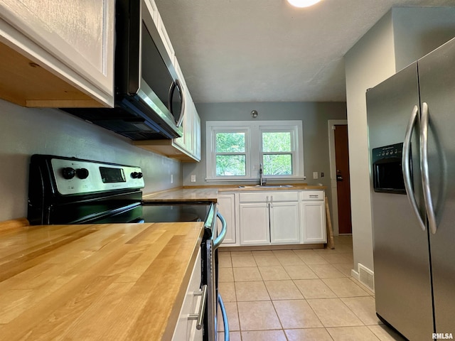 403 Freeman St, Anna, IL 62906 - kitchen with stainless steel appliances, butcher block countertops, white cabinets, and light tile patterned floors