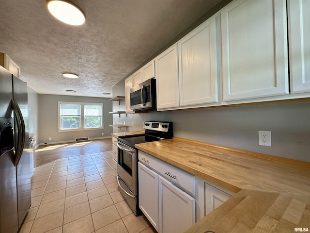 403 Freeman St, Anna, IL 62906 - kitchen with stainless steel appliances, wood counters, light tile patterned floors, white cabinets, and open floor plan