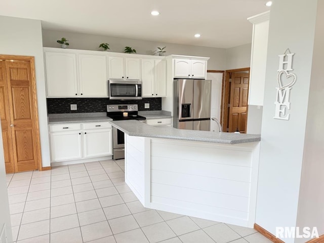 418 Michelle Ln, Walcott, IA 52773 - kitchen with stainless steel appliances, white cabinets, light countertops, decorative backsplash, and a peninsula