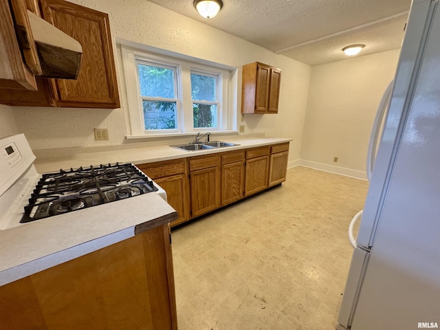 1100 E 2nd St, Centralia, IL 62801 - kitchen featuring freestanding refrigerator, gas range, brown cabinetry, light floors, and ventilation hood