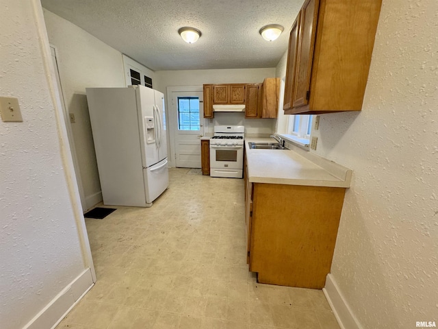 1100 E 2nd St, Centralia, IL 62801 - kitchen featuring white appliances, brown cabinetry, under cabinet range hood, light countertops, and a textured ceiling