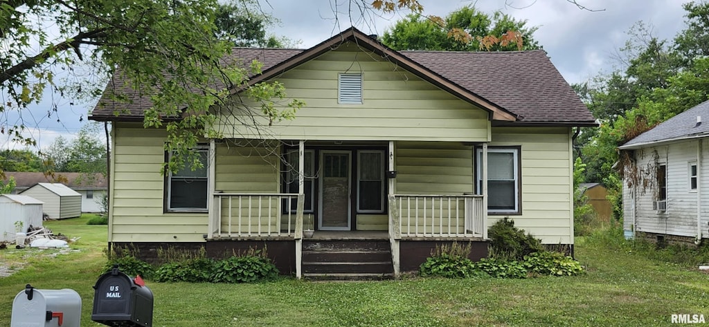 605 N Elm St, Sesser, IL 62884 - bungalow-style home with a porch, a front lawn, a shingled roof, and cooling unit