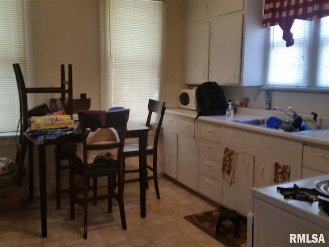 kitchen with light tile flooring, white cabinetry, and sink