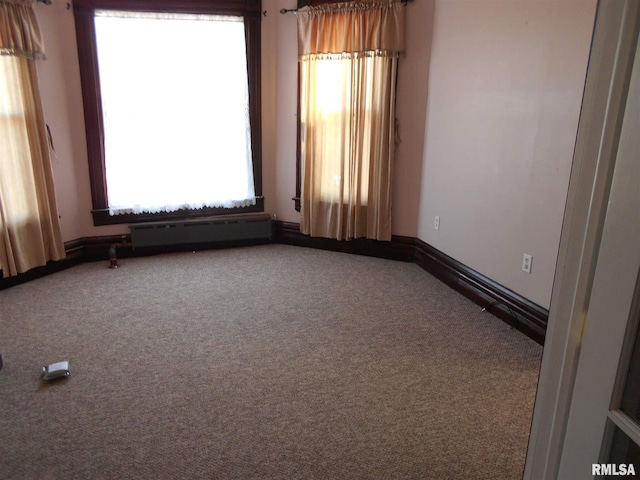 unfurnished room featuring a baseboard heating unit and dark colored carpet