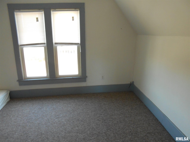 bonus room with lofted ceiling and dark carpet