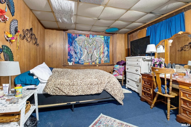 bedroom with wood walls, a drop ceiling, and carpet